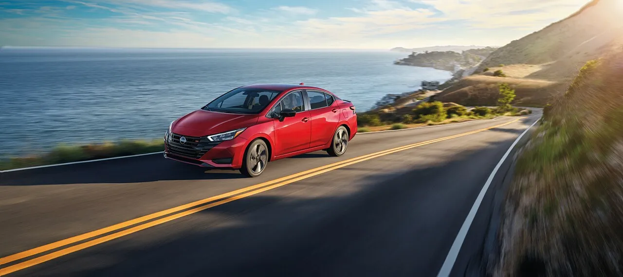 2025 Nissan Sentra Sedan Driving on Scenic Coast Red 2025 Nissan Sentra sedan driving on coastal highway