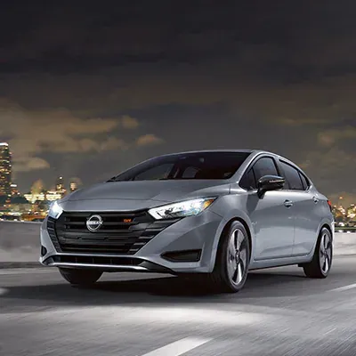 2025 Nissan Versa at night with LED headlights on a city highway