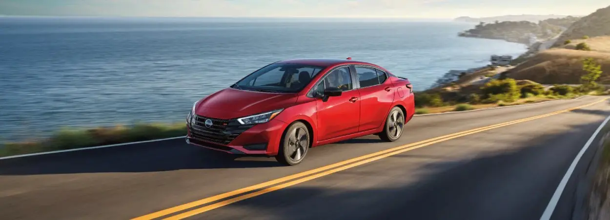 Red Nissan Sentra driving along coast