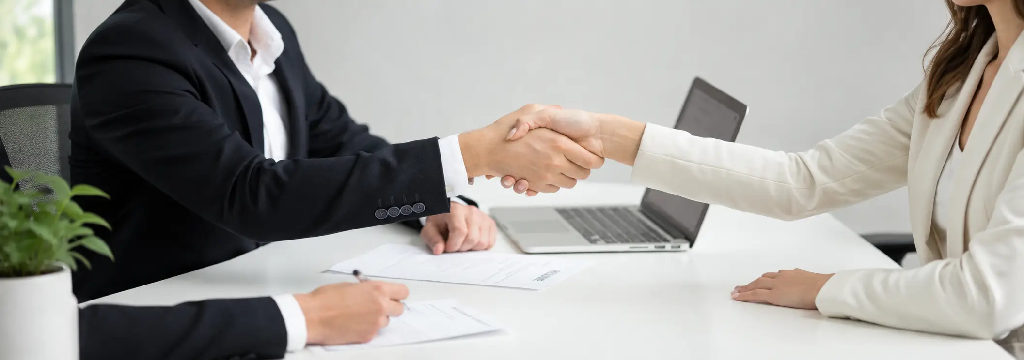 Careers at Old Orchard Nissan Two people shaking hands across a desk during a job interview