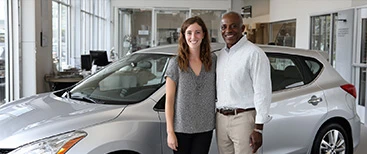 Happy customers standing next to new car