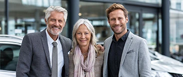 Three satisfied customers standing together at dealership