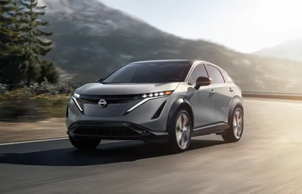 Silver nissan ariya electric suv driving on scenic road