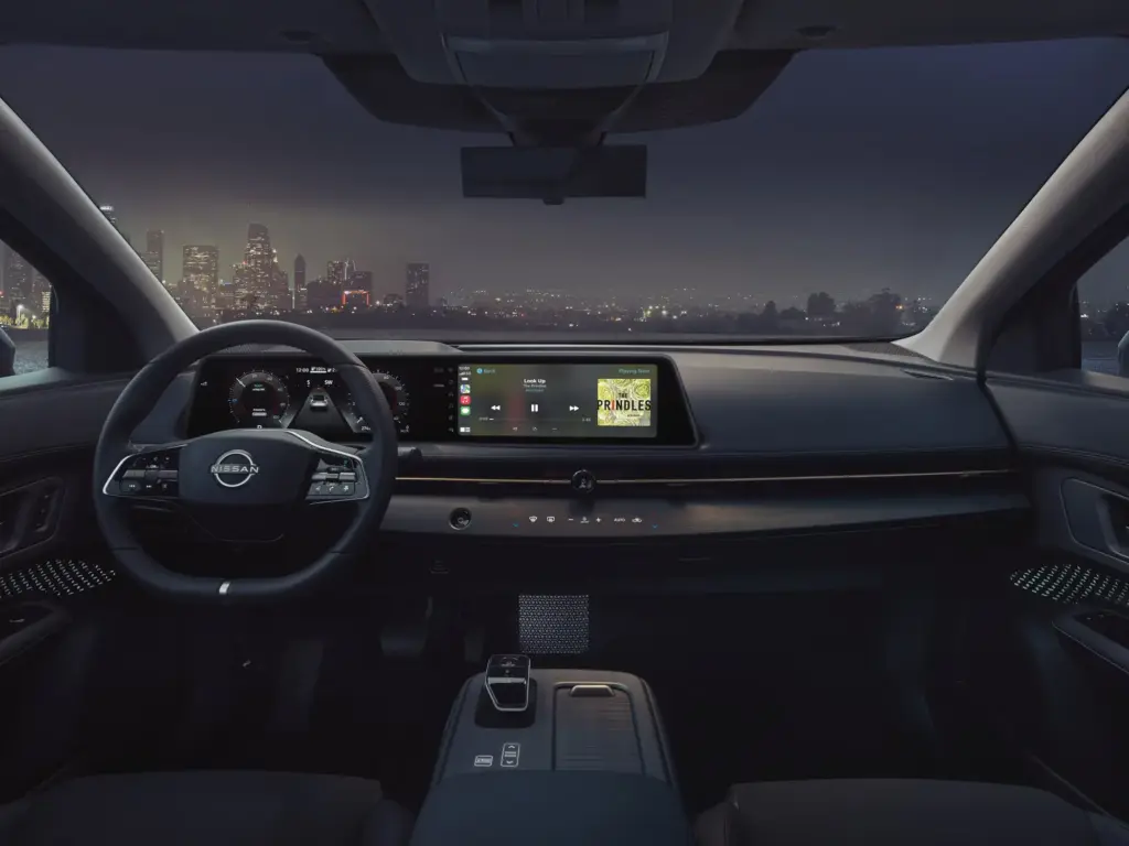 Nissan Ariya Interior Dashboard with Night City View Nissan Ariya interior dashboard with steering wheel, digital display, and city skyline visible through windshield at night