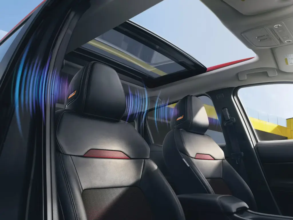 Nissan Front Seats with Headrest Speakers Front seats with integrated headrest speaker grilles and panoramic sunroof inside a Nissan vehicle