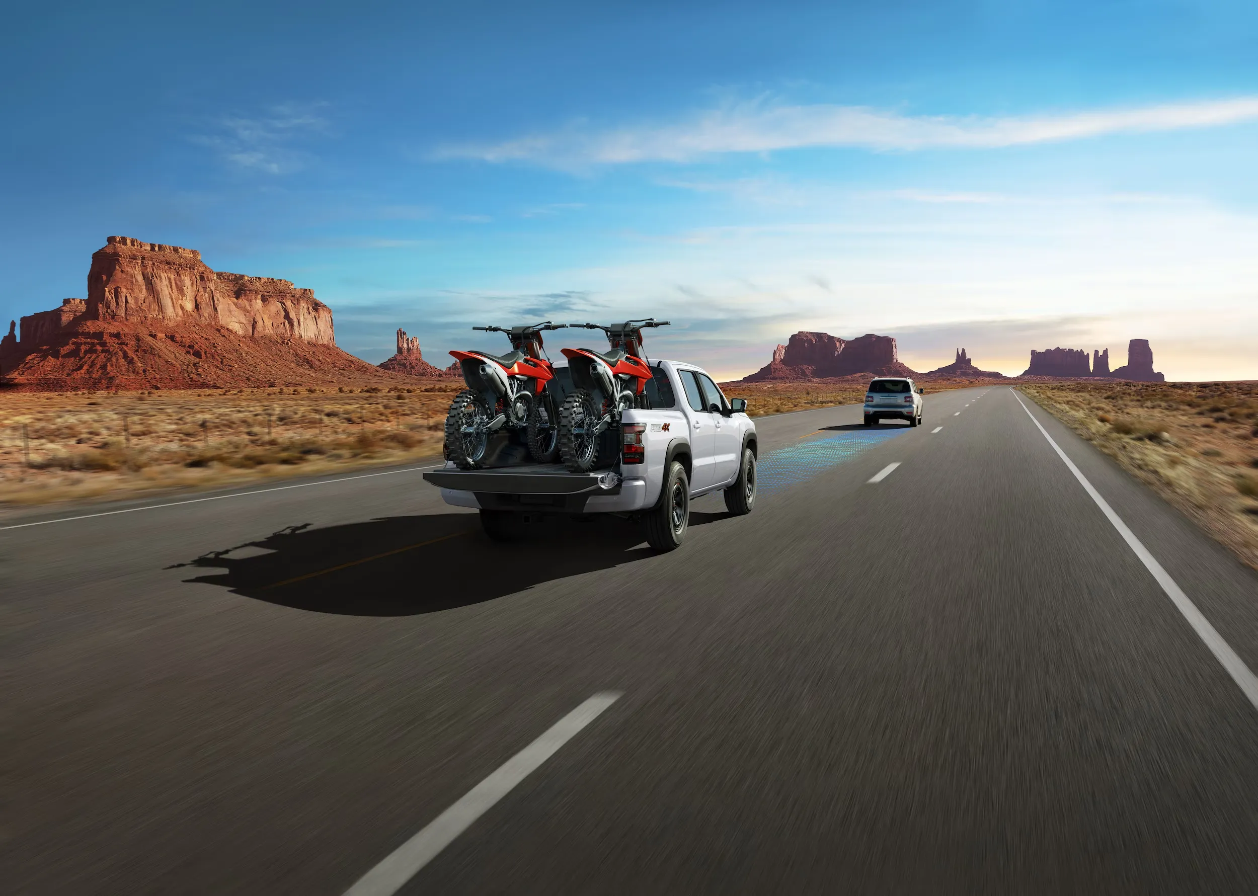 Nissan Frontier Hauling Dirt Bikes on Highway Nissan Frontier carrying two dirt bikes in truck bed