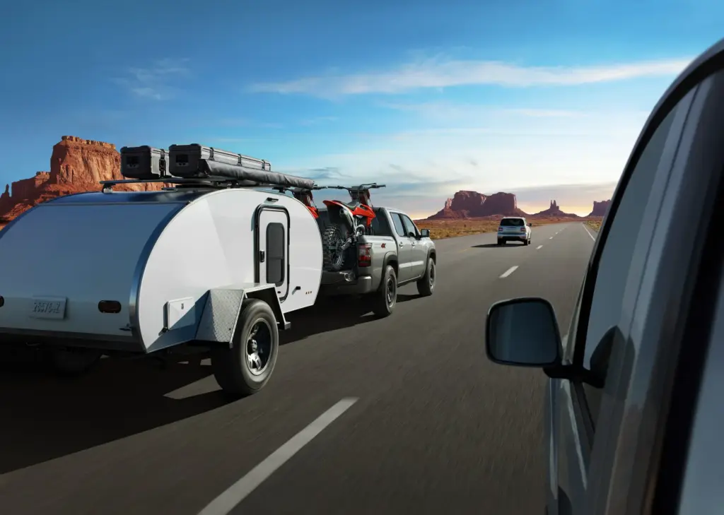 Nissan Frontier Towing Camper Trailer on Highway Nissan Frontier towing small camper trailer on open highway