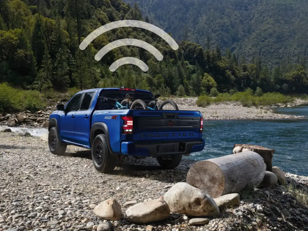 Nissan Frontier Built-In Wi-Fi Hotspot Connectivity Nissan Frontier parked by river with Wi-Fi hotspot signal