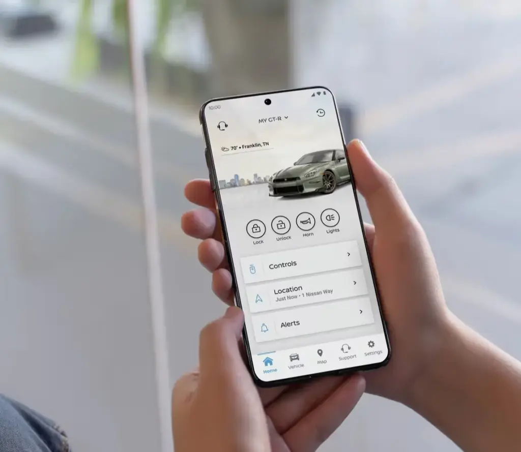 Nissan GT-R Mobile App Displaying Remote Vehicle Controls Person holding smartphone showing Nissan GT-R mobile app with lock and vehicle controls