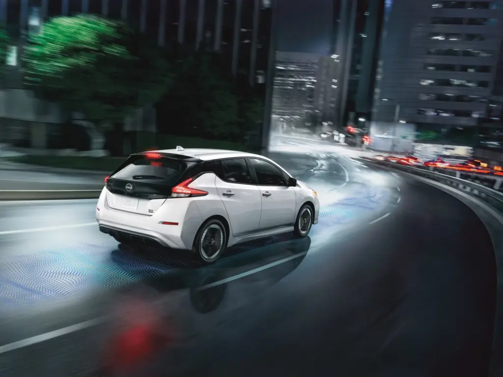 White Nissan Leaf Driving in City at Night White Nissan Leaf driving through city at night
