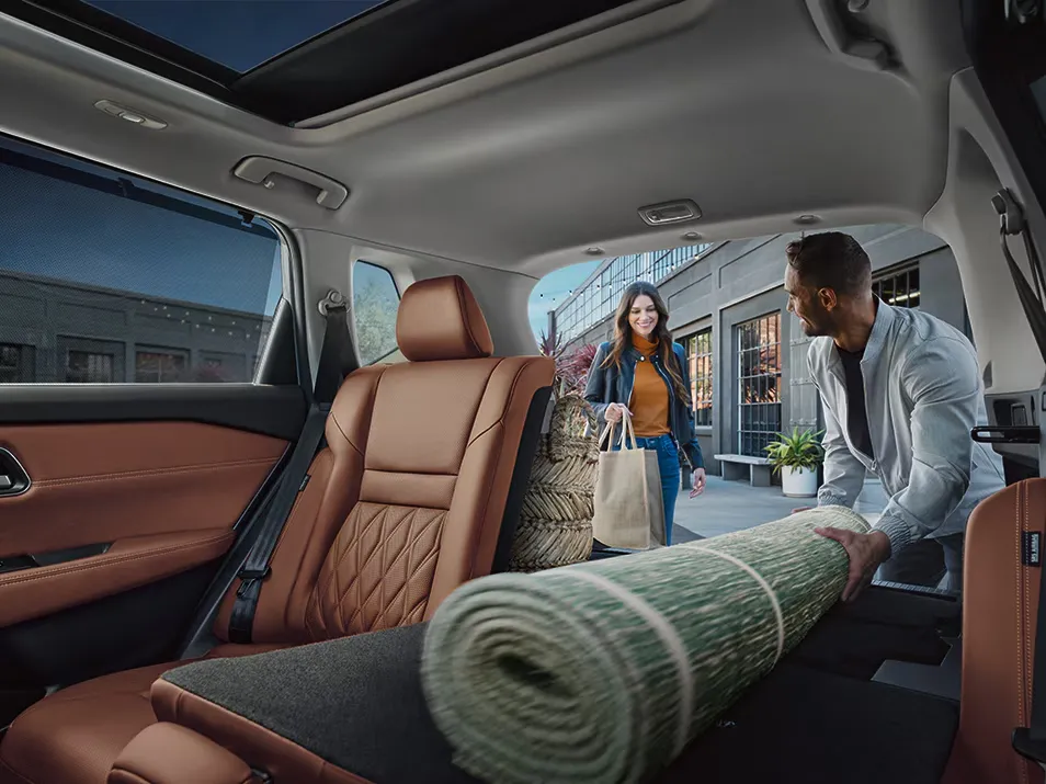Nissan SUV Flexible Cargo Space And Rear Seating Nissan SUV interior showing flexible cargo space as a couple loads a rolled rug into the rear seats after shopping