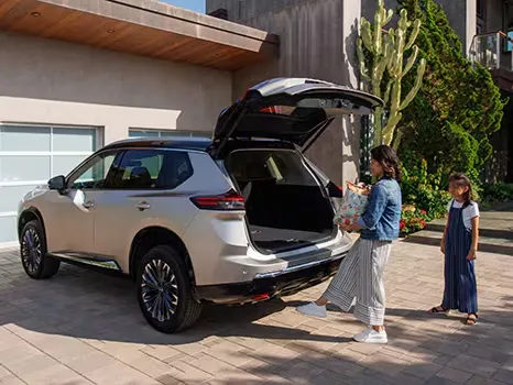 Nissan SUV Hands-Free Liftgate Convenience Family loading groceries into a Nissan SUV with an open rear liftgate at a modern home