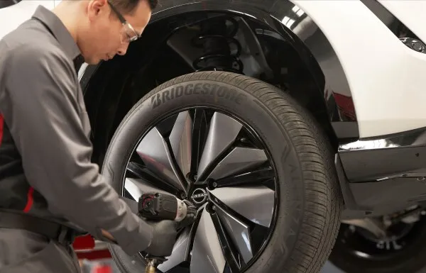 Nissan Tire and Wheel Service Appointment Technician installing wheel on nissan vehicle