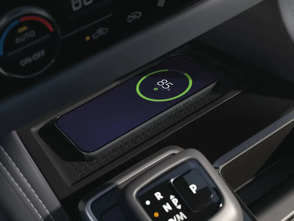 Smartphone on Wireless Charging Pad in Vehicle Center Console Smartphone charging wirelessly on a vehicle center console pad showing battery level